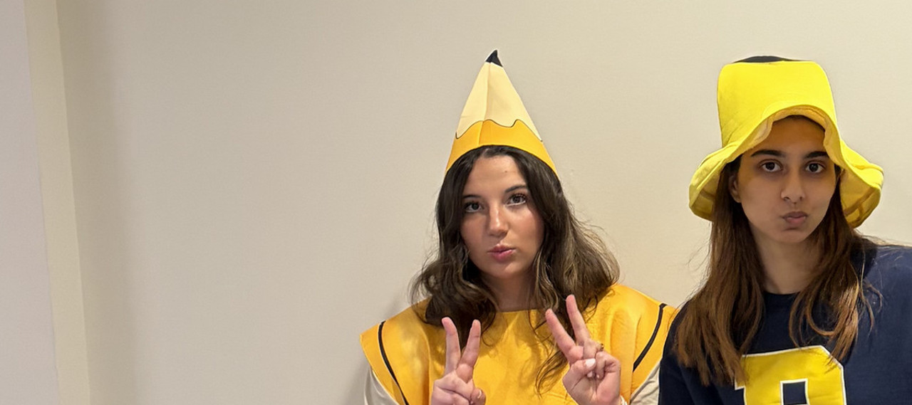 Writing fellows in pencil costumes giving peace signs, playfully.