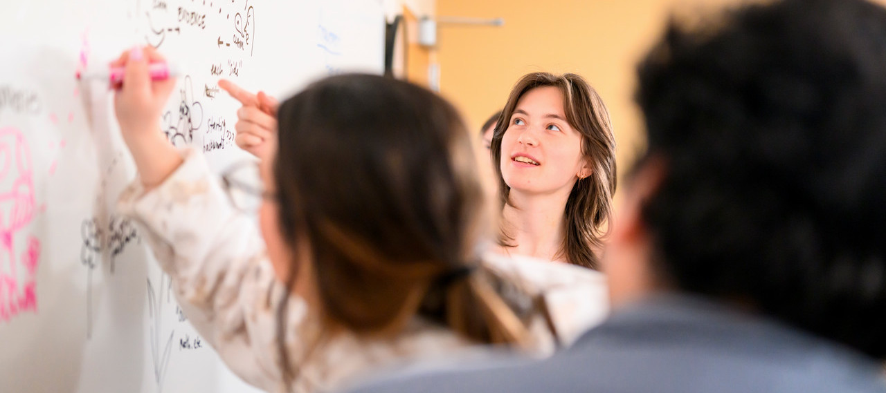 Writing course where students are writing on a white board and talking to each other about arguments and evidence